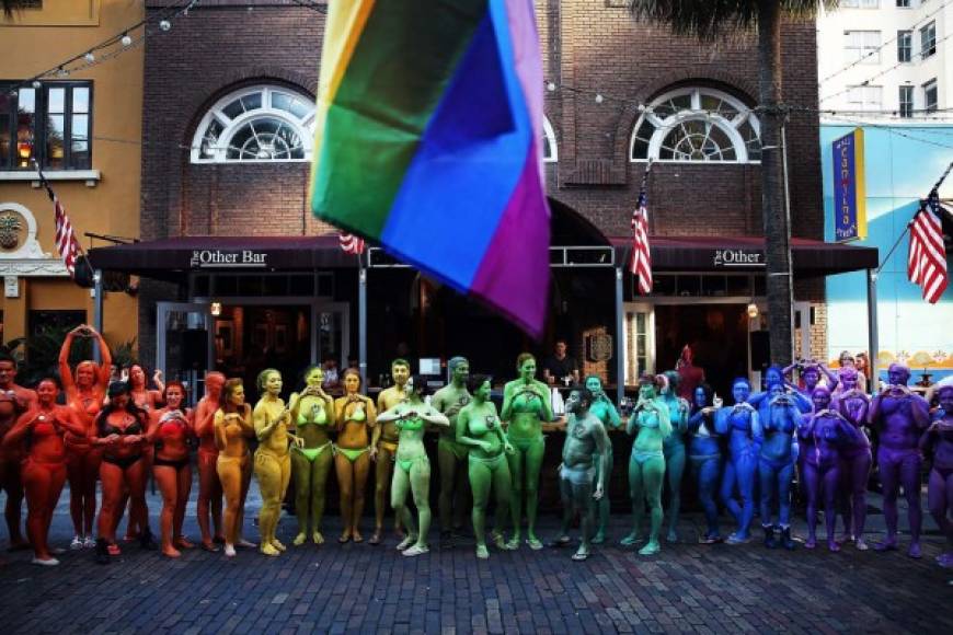 Un grupo de jóvenes se pintaron con los colores del arcoíris y posaron frente a un bar.