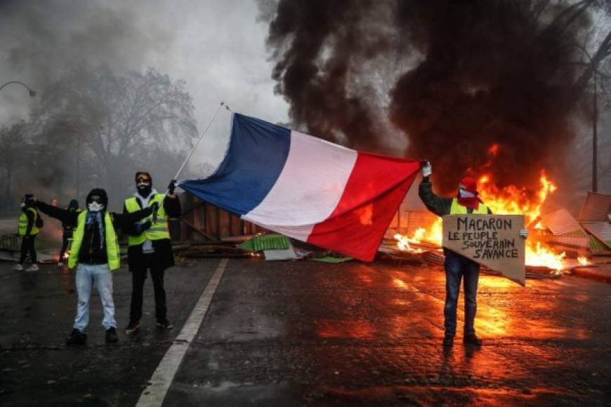 Protesters hold a French flag near a burning barricade during a protest of Yellow vests (Gilets jaunes) against rising oil prices and living costs, on December 1, 2018 in Paris. (Photo by Abdulmonam EASSA / AFP)