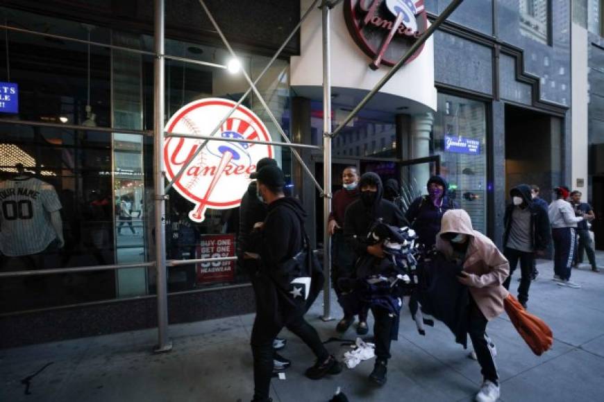 TOPSHOT - Protesters loot a NY Yankee store during demonstrations over the death of George Floyd by a Minneapolis police officer on June 1, 2020 in New York. - New York's mayor Bill de Blasio today declared a city curfew from 11:00 pm to 5:00 am, as sometimes violent anti-racism protests roil communities nationwide.<br/>Saying that 'we support peaceful protest,' De Blasio tweeted he had made the decision in consultation with the state's governor Andrew Cuomo, following the lead of many large US cities that instituted curfews in a bid to clamp down on violence and looting. (Photo by Bryan R. Smith / AFP)