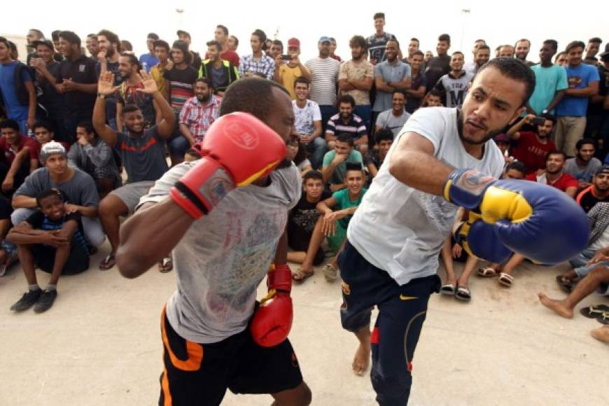 BOXEO. Peleas callejeras. Libios protagonizan un combate de boxeo en una calle de la ciudad costera de Benghazi ante un público que disfruta de los golpes. Foto: AFP/Abdullah Doma