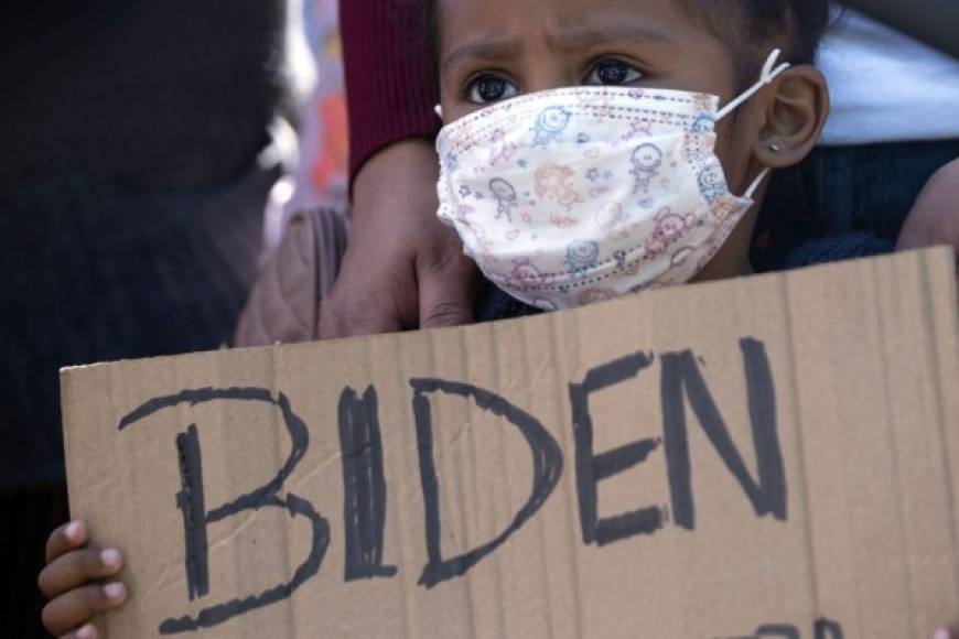 Dareli Matamoros, una niña de Honduras, sostiene un cartel pidiendo al presidente Biden que la deje entrar durante una manifestación de migrantes en el puerto de cruce de San Ysidro en Tijuana, Baja California. AFP