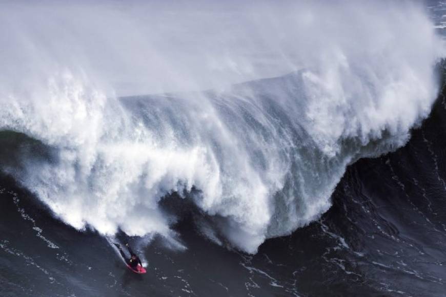 Un surfista monta las gigantescas olas en las playas de la Bahía de Nazaré en Brasil.