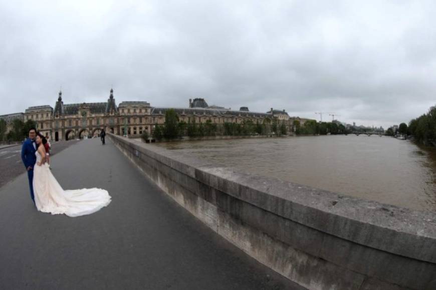 Una pareja de recién casados ​​se coloca en un puente en París y posa para el recuerdo. AFP