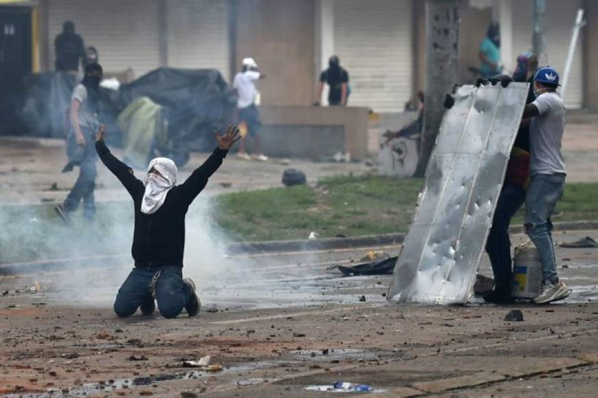 (FILES) In this file photo taken on May 3, 2021 Demonstrators clash with riot police during a protest against a tax reform bill launched by President Ivan Duque, despite the president then ordered the proposal be withdrawn from Congress, in Cali, Colombia. - The United States on May 4, 2021 urged authorities in Colombia to act with 'utmost restraint' to avoid more deaths during anti-government protests that have resulted in at least 19 fatalities. (Photo by Luis ROBAYO / AFP)