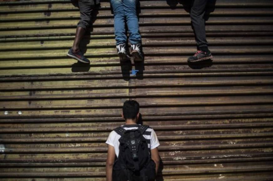 A group of Central American migrants -mostly Hondurans- climb the border fence between Mexico and the United States, near El Chaparral border crossing, in Tijuana, Baja California State, Mexico, on November 25, 2018. - Hundreds of migrants attempted to storm a border fence separating Mexico from the US on Sunday amid mounting fears they will be kept in Mexico while their applications for a asylum are processed. An AFP photographer said the migrants broke away from a peaceful march at a border bridge and tried to climb over a metal border barrier in the attempt to enter the United States. (Photo by Pedro PARDO / AFP)