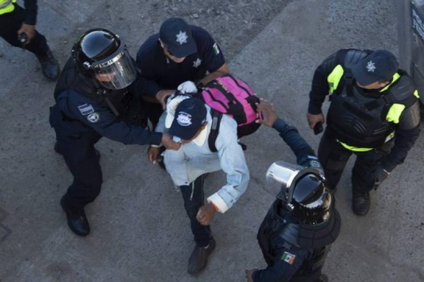 A Central American migrant struggles with Mexican police forces as he reaches the El Chaparral border crossing, in Tijuana, Baja California State, Mexico, on November 25, 2018. - Hundreds of migrants attempted to storm a border fence separating Mexico from the US on Sunday amid mounting fears they will be kept in Mexico while their applications for a asylum are processed. An AFP photographer said the migrants broke away from a peaceful march at a border bridge and tried to climb over a metal border barrier in the attempt to enter the United States. (Photo by Pedro PARDO / AFP)