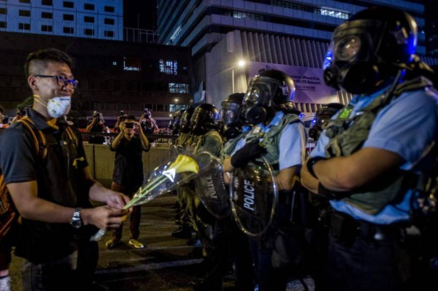 Un manifestante se mofa de los policías desplegados por las autoridades para controlar las masivas protestas que han paralizado la ciudad de Hong Kong.