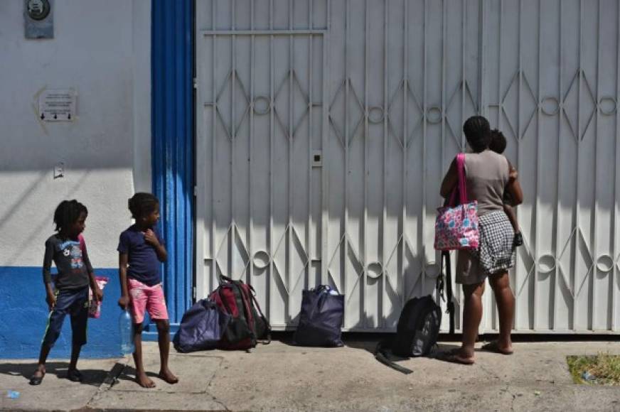 Una mujer migrante haitiana y sus hijos esperan afuera de la oficina de migraciones en Choluteca, Honduras.