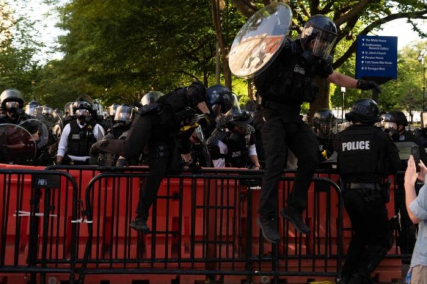Riot police jump over a barricade to confront protestors near the White House on June 1, 2020 as demonstrations against George Floyd's death continue. - Police fired tear gas outside the White House late Sunday as anti-racism protestors again took to the streets to voice fury at police brutality, and major US cities were put under curfew to suppress rioting.With the Trump administration branding instigators of six nights of rioting as domestic terrorists, there were more confrontations between protestors and police and fresh outbreaks of looting. Local US leaders appealed to citizens to give constructive outlet to their rage over the death of an unarmed black man in Minneapolis, while night-time curfews were imposed in cities including Washington, Los Angeles and Houston. (Photo by ROBERTO SCHMIDT / AFP)