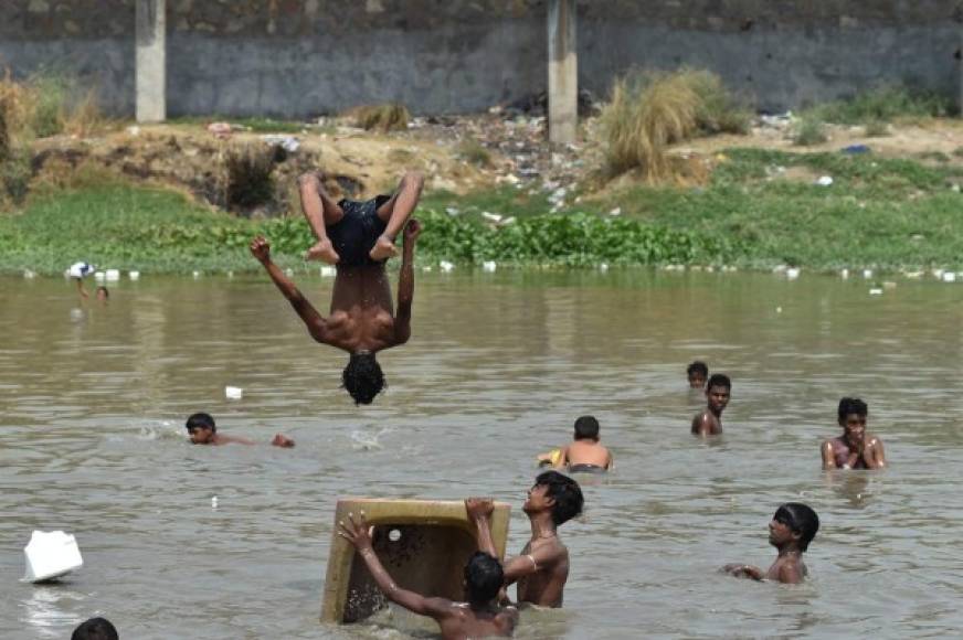 Niños indios disfrutan de un baño en un estanque para escapar del calor en Nueva Delhi.