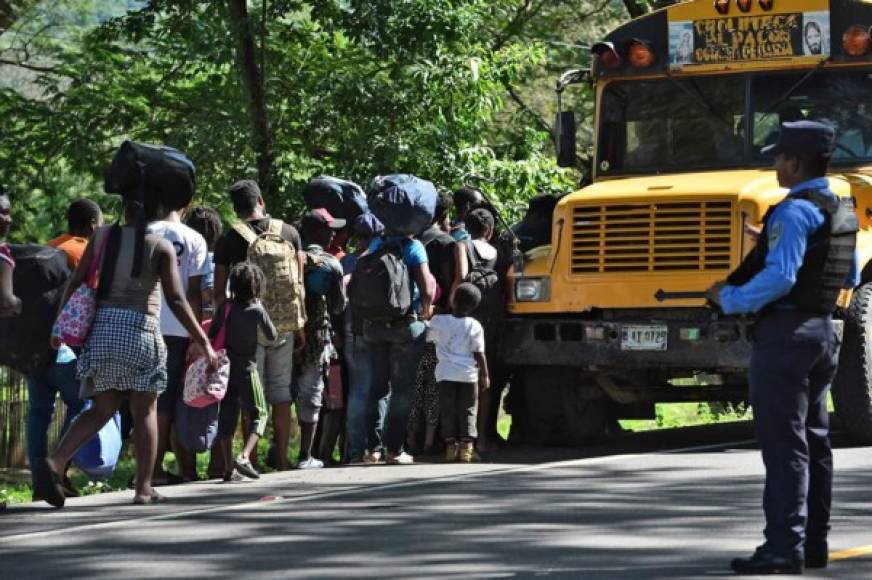 Migrantes africanos y haitianos abordan un autobús después de pasar por un 'cruce ciego' de Nicaragua a Honduras en su camino a los Estados Unidos, mientras los agentes de policía hacen guardia en Guasaule, Honduras el 16 de noviembre de 2019.