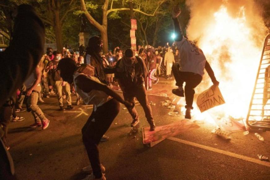 TOPSHOT - Protesters jump on a street sign near a burning barricade during a demonstration against the death of George Floyd near the White House on May 31, 2020 in Washington, DC. - Thousands of National Guard troops patrolled major US cities after five consecutive nights of protests over racism and police brutality that boiled over into arson and looting, sending shock waves through the country. The death Monday of an unarmed black man, George Floyd, at the hands of police in Minneapolis ignited this latest wave of outrage in the US over law enforcement's repeated use of lethal force against African Americans -- this one like others before captured on cellphone video. (Photo by ROBERTO SCHMIDT / AFP)