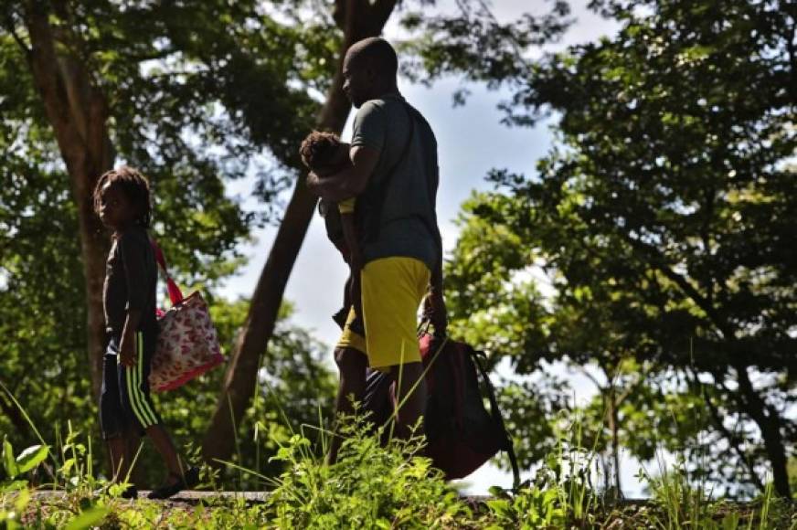 Un hombre migrante africano y sus hijos permanecen al costado de una carretera después de pasar por un 'cruce ciego' de Nicaragua a Honduras en su camino a los Estados Unidos, en Guasaule, Honduras, el 16 de noviembre de 2019.