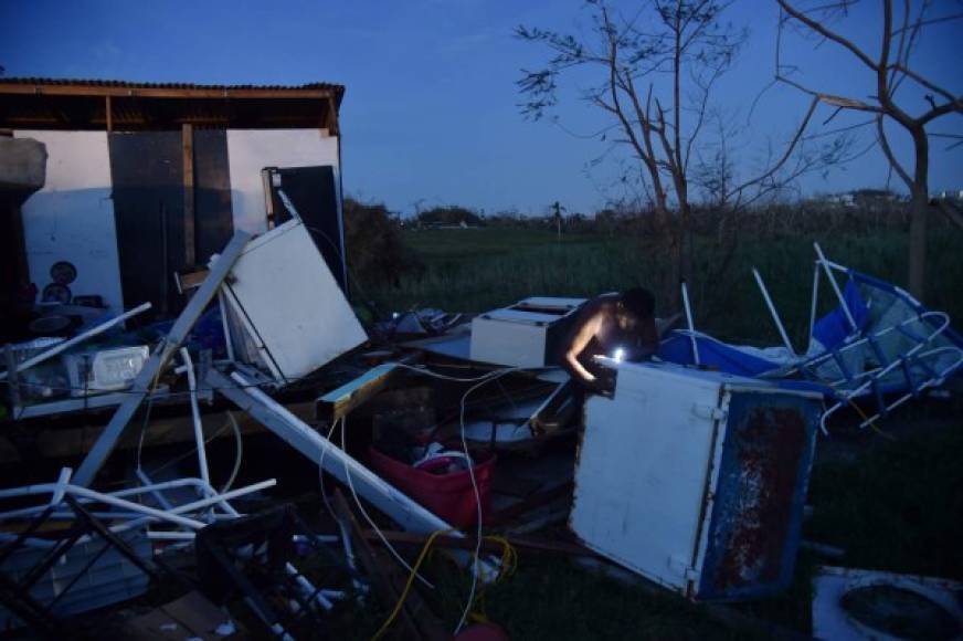A man tries to repair a freezer during nightfall outside his home on September 25, 2017 in Toa Alta, Puerto Rico, following passage of Hurricane Maria.<br/>The US island territory, working without electricity, is struggling to dig out and clean up from its disastrous brush with the hurricane, blamed for at least 33 deaths across the Caribbean. / AFP PHOTO / HECTOR RETAMAL
