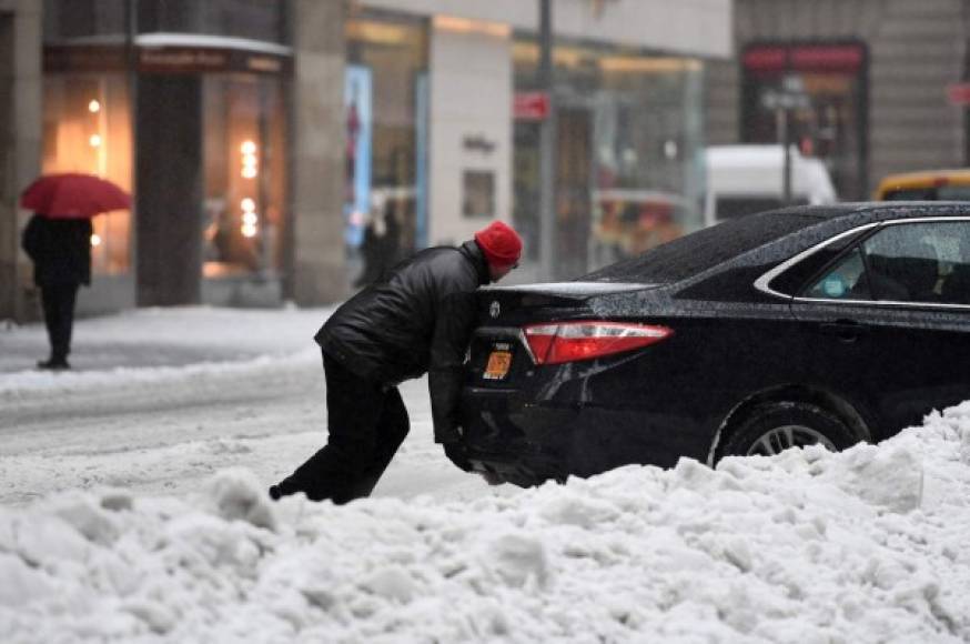 A pedestrian tries to help a car stuck on a snow and sleet-covered street in New York on March 14, 2017.<br/>Winter Storm Stella dumped sleet and snow across the northeastern United States on Tuesday but spared New York from the worst after authorities cancelled thousands of flights and shut schools. Blizzard warnings were in effect in parts of Connecticut, Massachusetts and upstate New York, but were lifted for New York City, the US financial capital home to 8.4 million residents, where snow turned to sleet, hail and rain.<br/> / AFP PHOTO / Jewel SAMAD