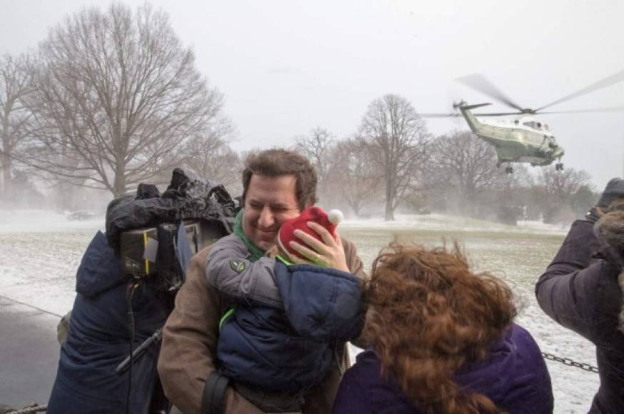Turistas se protegen de la nieve lanzada por el Marine One mientras despegaba en Washington DC.