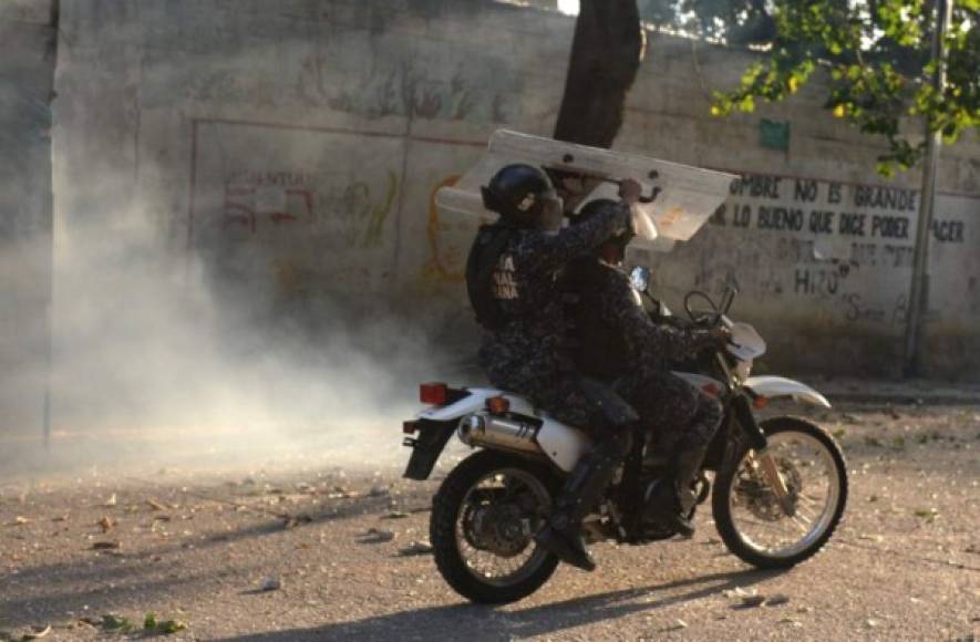 Riot police on a motorcycle hold a shield during clashes with anti-government demonstrators in the neighborhood of Los Mecedores, in Caracas, on January 21, 2019. - A group of soldiers rose up against Venezuela's President Nicolas Maduro at a command post in northern Caracas on Monday, but were quickly arrested after posting an appeal for public support in a video, the government said. (Photo by Federico Parra / AFP)