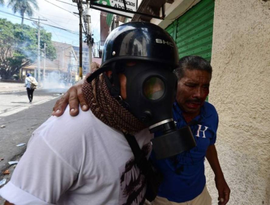 Un periodista auxilia a un hombre que fue herido durante las protestas.