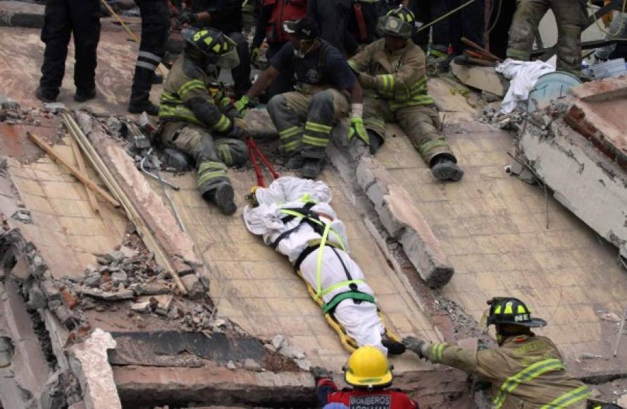 TOPSHOT - Rescuers and firefighters lower the corpse from a house that was destroyed after a powerful quake in Mexico City on September 20, 2017.<br/>A devastating quake in Mexico on Tuesday killed more than 100 people, according to official tallies, with a preliminary 30 deaths recorded in the capital where rescue efforts were still going on. / AFP PHOTO / Victor GALINDO