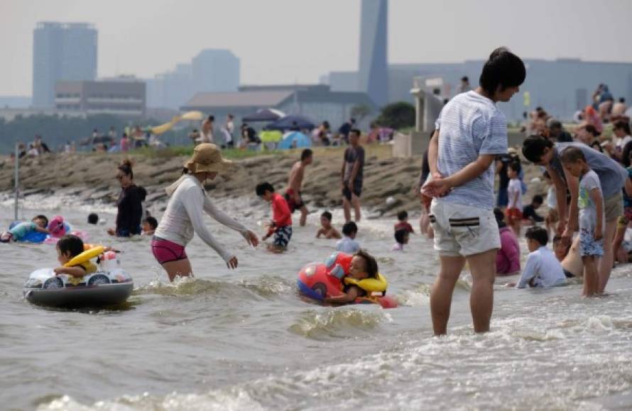 Families swim and play in the water at a seaside park in Tokyo on July 22, 2018.<br/>Japan's severe heatwave killed at least 15 people and sent more than 12,000 to hospital in the first two weeks of July, official figures show as the temperature neared 40 degrees C (104 F) in many cities on July 22. <br/> / AFP PHOTO / Kazuhiro NOGI