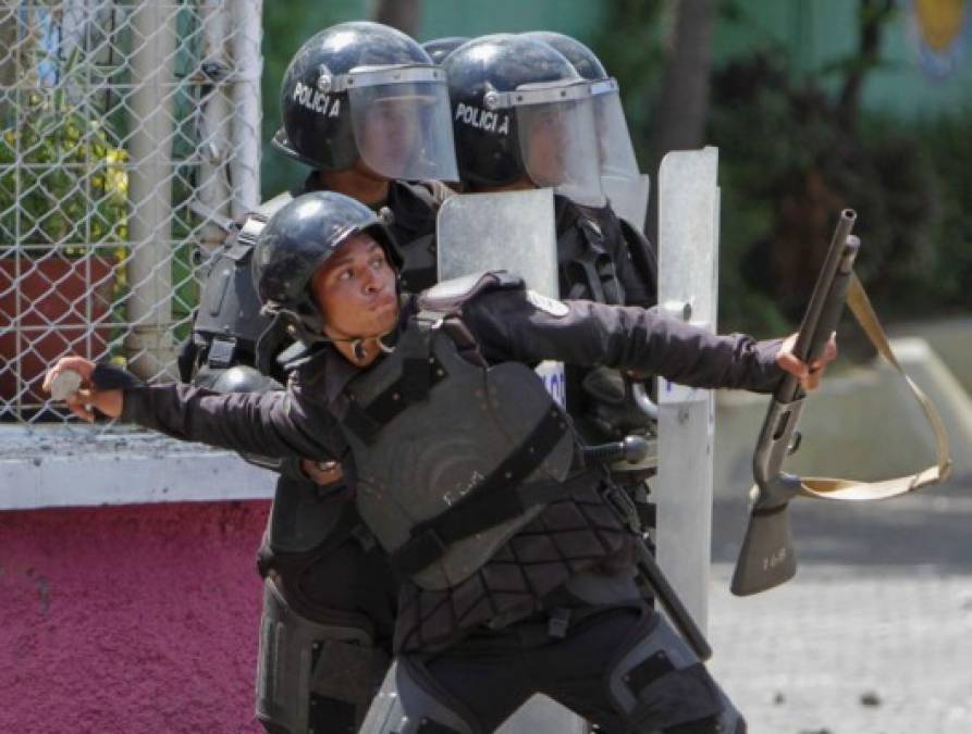 A policeman throws a stone to students in front of the university of engineering who protest the government's reforms in the Institute of Social Security (INSS) in Managua on April 19, 2018. / AFP PHOTO / Inti Ocon