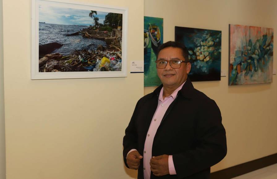 Agustín Ortega posa junto a su fotografía, la cual muestra la contaminación en Puerto Cortés. 