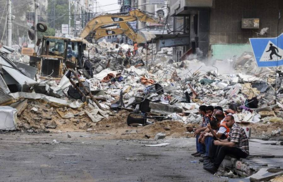 Una excavadora limpia los escombros de un edificio destruido en el distrito residencial Rimal de la ciudad de Gaza el 16 de mayo de 2021, luego del bombardeo masivo israelí en el enclave controlado por Hamas. - Los ataques israelíes mataron a 40 palestinos en la Franja de Gaza, la peor cifra diaria de muertos reportada hasta ahora en los enfrentamientos de casi una semana, mientras el Consejo de Seguridad de la ONU se preparaba para reunirse en medio de la alarma mundial por la escalada del conflicto. (Foto de Mahmud Hams / AFP)