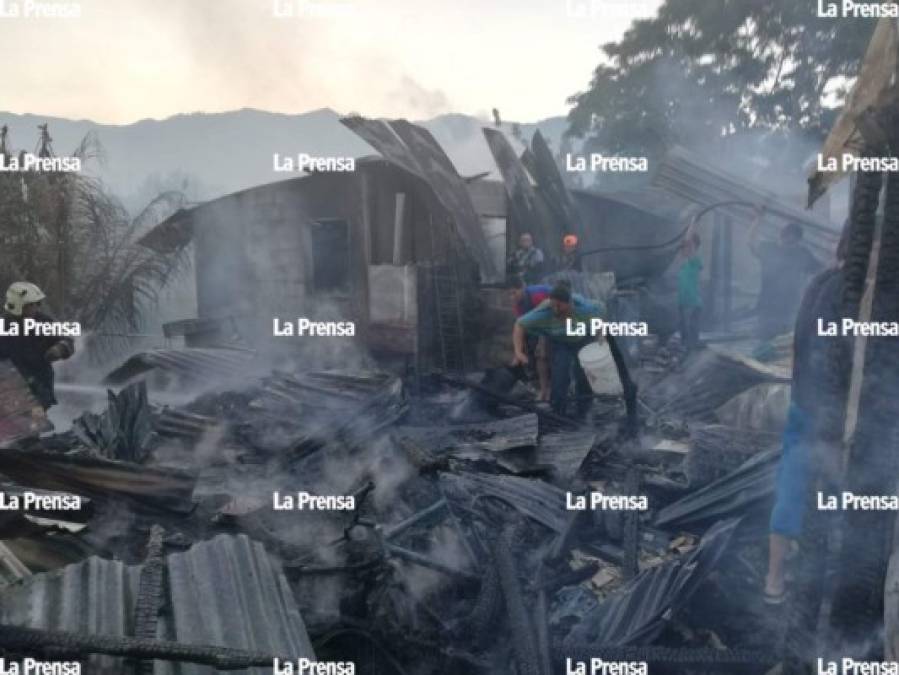 Vecinos del lugar caminan entre los restos humeantes de las viviendas incendiadas.