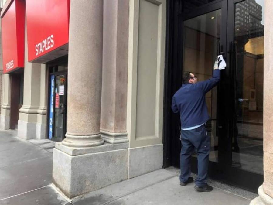 Un hombre limpia la puerta de un edificio este jueves en el centro de Manhattan, Nueva York (EE.UU).
