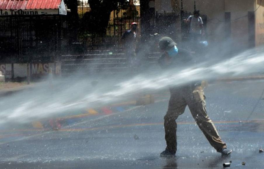 Un hombre recibe un chorro de agua a presión de parte de policías que dispersaron a los manifestantes.