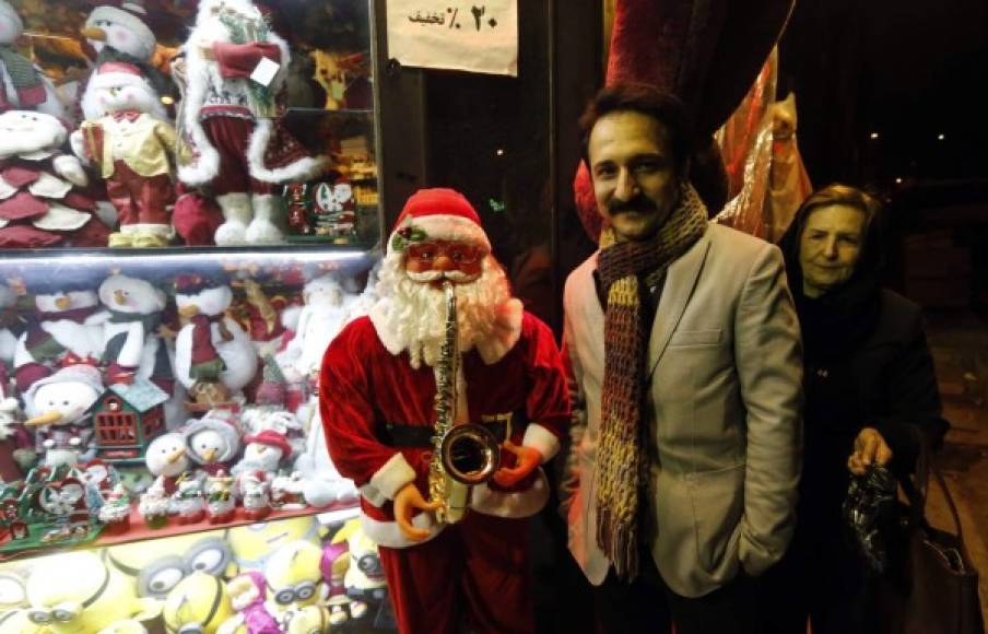 IRÁN. Lleno de espíritu navideño. Un iraní posa para una foto al lado de una estatua de Papá Noel fuera de una tienda en la capital Teherán. Foto: AFP