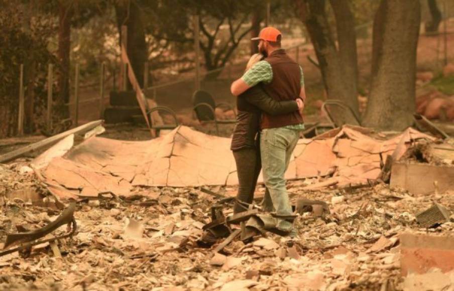 Chris and Nancy Brown embrace while looking over the remains of their burned residence after the Camp fire tore through the region in Paradise, California on November 12, 2018. - Thousands of firefighters spent a fifth day digging battle lines to contain California's worst ever wildfire as the wind-whipped flames cleaved a merciless path through the state's northern hills, leaving death and devastation in their wake. The Camp Fire -- in the foothills of the Sierra Nevada mountains north of Sacramento -- has killed 29 people, matching the state's deadliest ever brush blaze 85 years ago. More than 200 people are still unaccounted for, according to officials. (Photo by Josh Edelson / AFP)