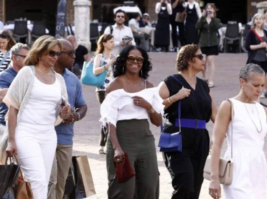 Para visitar la catedral de Siena, Michelle optó por atuendo veraniego compuesto por pantalones palazzo verde olivo, una blusa blanca con los hombros al descubierto y vuelos, llamativos lentes redondos y un minibolso rojo vino de gamuza.