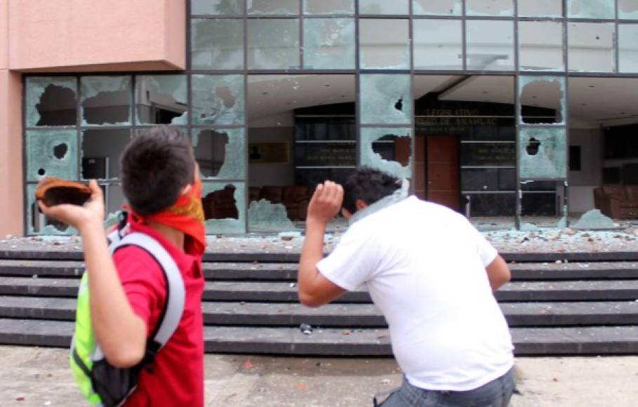 Encapuchados lanzan piedras contra la sede del Congreso de Guerrero.