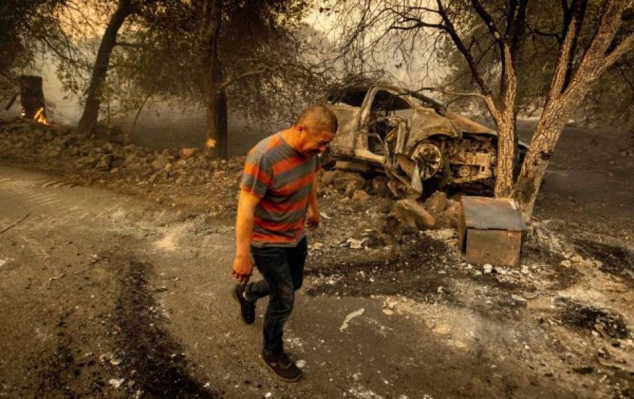 TOPSHOT - Resident Osvaldo Ramirez walks away from his burned vehicle during the Glass fire in St. Helena, California on September 27, 2020. - Ramirez stated $8,000 in cash along with his family's papers that were located in a safe inside the vehicle, were burned. A wildfire with a 'dangerous rate of spread' broke out in Napa County between Calistoga and St. Helena overnight on September 27, 2020 just as the Bay Area braces for extreme wildfire conditions. (Photo by JOSH EDELSON / AFP)