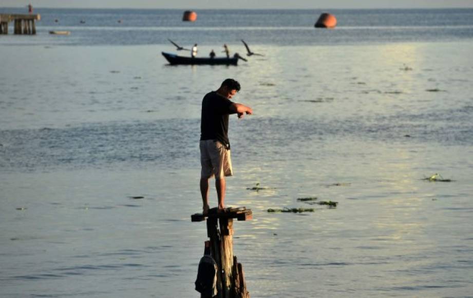 Un hombre pesca sobre los restos del zanco de un antiguo muelle, en el municipio de Tela. AFP