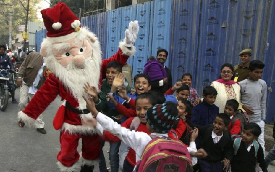 Un hombre vestido de Papa Noel bail junto a unos niños durante una marcha de Navidad en Jammu, capital de invierno de la India.