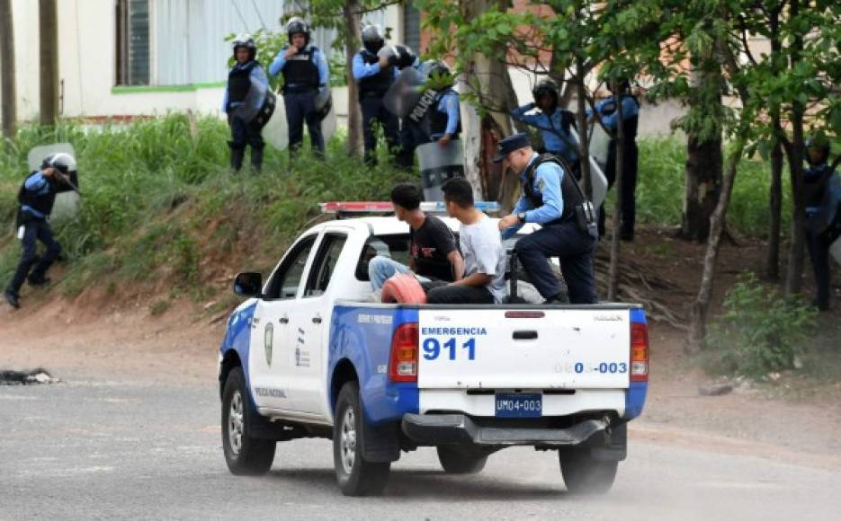 Los dos detenidos son llevados en una patrulla de la Policía.