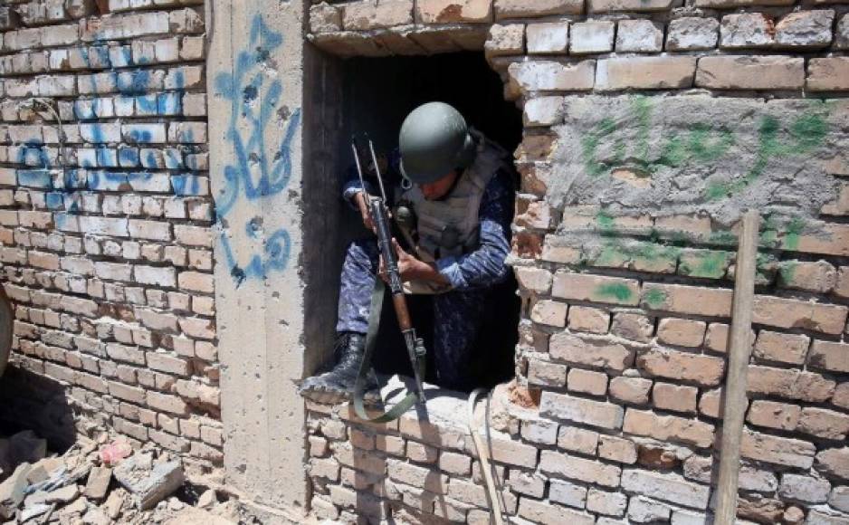 Un soldado salta por la ventana de una casa en ruinas.