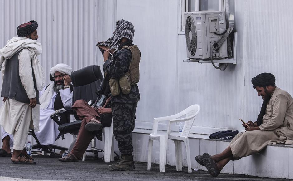 Miembros de los talibanes se sientan en un puesto de control cerca del aeropuerto de Kabu.
