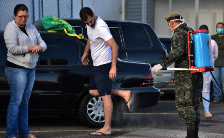 Soldadores desinfectan los pies de un hombre antes de ingresar al supermercado en Tegucigalpa.