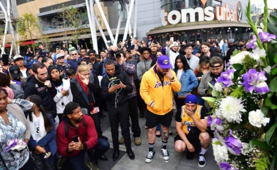 People gather around a makeshift memorial for former NBA and Los Angeles Lakers player Kobe Bryant after learning of his death at LA Live plaza in front of Staples Center in Los Angeles on January 26, 2020. - NBA legend Kobe Bryant died January 26, 2020 in a helicopter crash in suburban Los Angeles, celebrity website TMZ reported, saying five people are confirmed dead in the incident. (Photo by Frederic J. Brown / AFP)