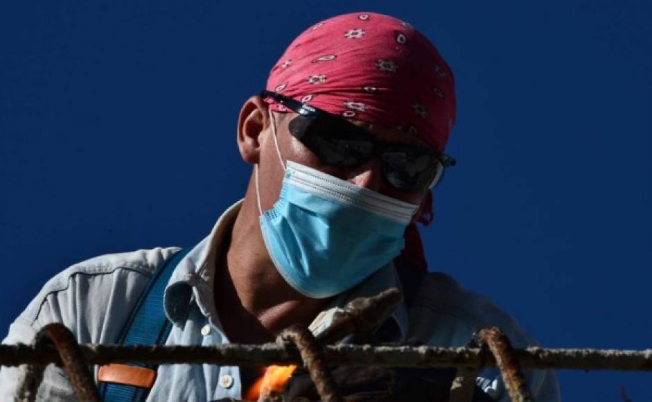 Un trabajador usa una máscara facial en el sitio de construcción de un puente en Tegucigalpa. Foto AFP