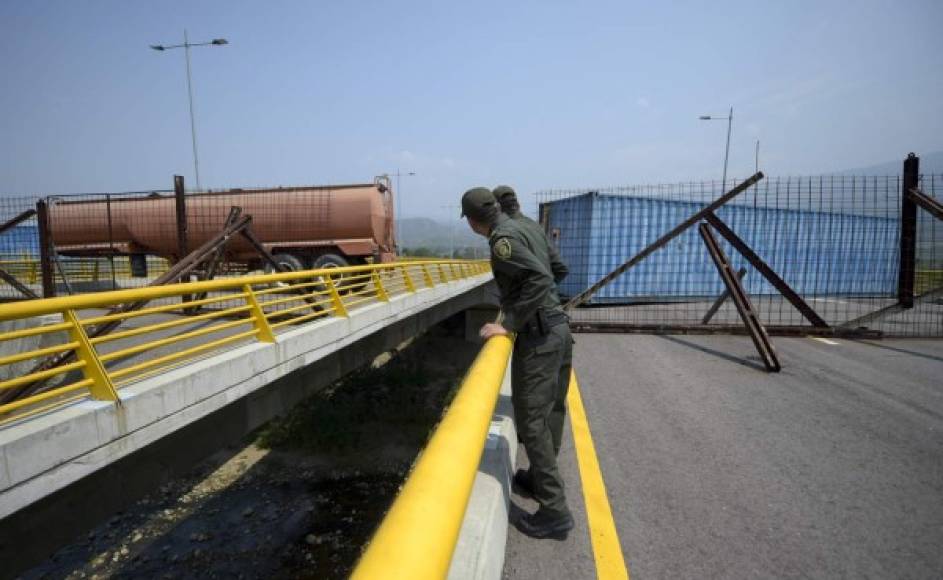 Colombian policemen look at the Tienditas Bridge, which links Tachira, Venezuela, and Cucuta, Colombia, after it was blocked with containers by Velezuelan forces, on February 6, 2019. - Venezuelan military officers blocked a bridge on the border with Colombia ahead of an anticipated humanitarian aid shipment, as opposition leader Juan Guaido stepped up his challenge to President Nicolas Maduro's authority. (Photo by Raul Arboleda / AFP)