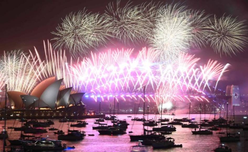 New Year's Eve fireworks erupt over Sydney's iconic Harbour Bridge and Opera House (L) during the fireworks show on January 1, 2020. (Photo by PETER PARKS / AFP)
