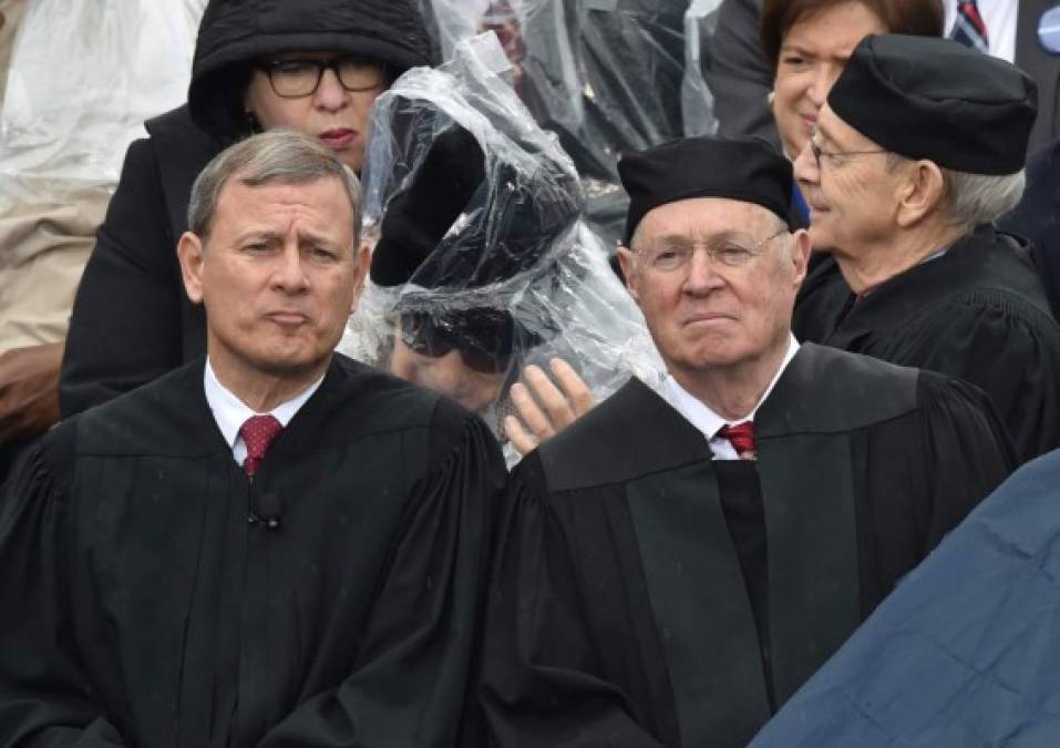 Los magistrados de la Corte Suprema de los Estados Unidos tratan de protegerse de la lluvia que cayó durante la ceremonia.