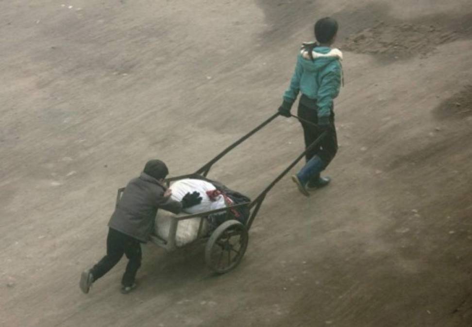 Unos niños empujan una carreta con víveres en una zona rural del país.