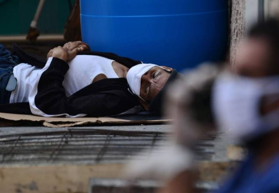Un hombre con síntomas de COVID-19 yace en el piso afuera del Hospital Escuela de Tegucigalpa. AFP