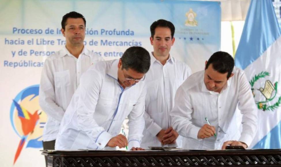 Handout picture released by Honduras' Presidency shows Honduran President Juan Orlando Hernandez (L) and his Guatemalan counterpart Jimmy Morales signing documents during the inauguration of a bilateral customs union in Corinto, Cortes Department, Honduras, on June 26, 2017.<br/>Guatemala and Honduras are officially opening their borders for the free circulation of goods, being the first Central American countries to accomplish the pursued aim of a customs union. / AFP PHOTO / Honduran Presidency / HO / RESTRICTED TO EDITORIAL USE - MANDATORY CREDIT 'AFP PHOTO / HONDURAN PRESIDENCY' - NO MARKETING NO ADVERTISING CAMPAIGNS - DISTRIBUTED AS A SERVICE TO CLIENTS<br/><br/>