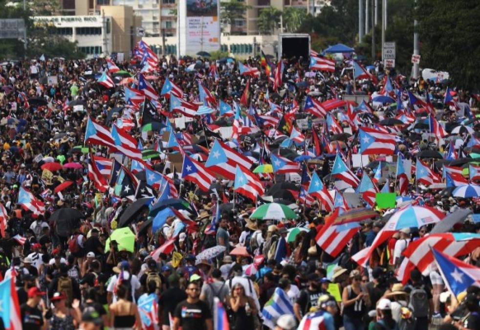 Los manifestantes llevaban la bandera puertorriqueña y cantaban consignas como 'Ricky no está aquí, Ricky está vendiendo lo que queda del país'.